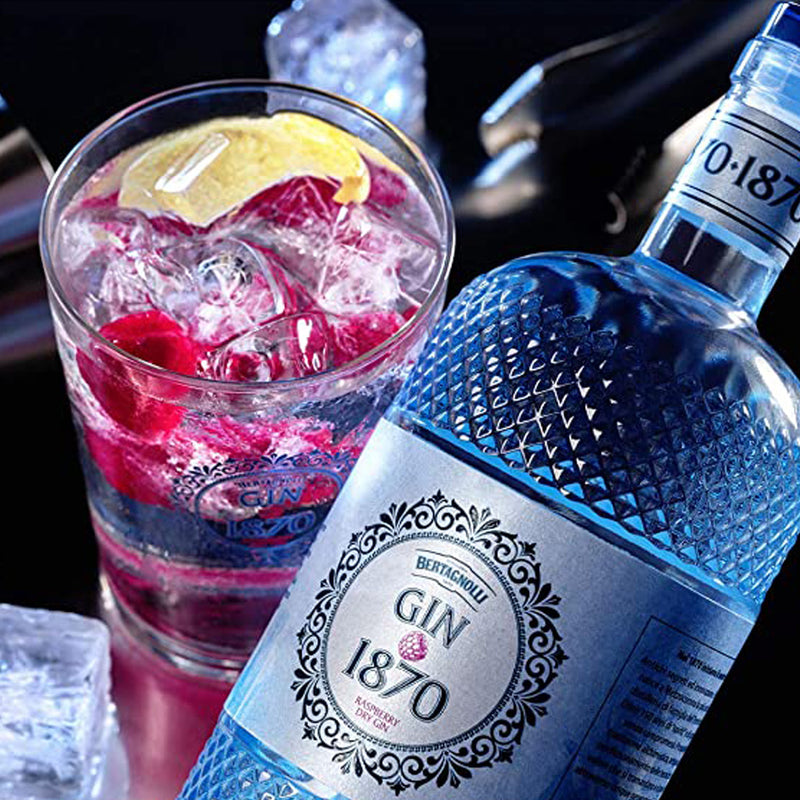 Gin Flasche mit Ginglas, das den Drink mit Himbeeren zeigt.