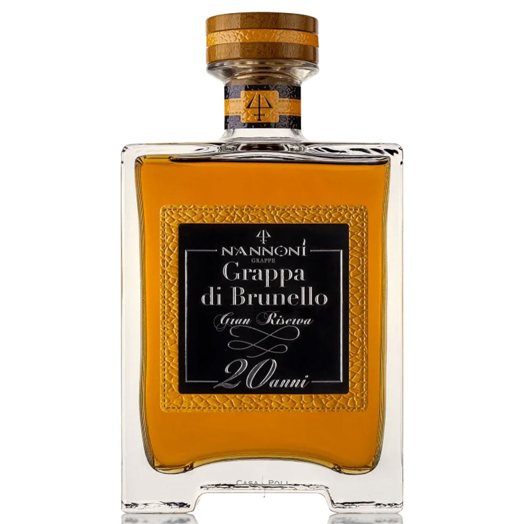 Elegante, schlanke 0.7-l-Flasche mit tiefem Bernsteinfarbton, warm ausgeleuchtet auf dunklem Holz. Im Hintergrund angedeutete Barriquefässer für ein hochwertiges, edles Ambiente.
